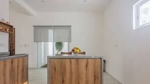A modern kitchen with wooden cabinets, a granite countertop, and a fruit bowl.