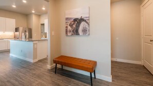 A spacious kitchen with modern appliances, a central island, and a bench in the hallway. - The Slowdown Saddle - Hot Tub (Lubbock)