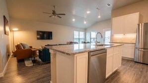 A modern kitchen with a central island, built-in appliances, and a dining area with a sofa and chairs. - The Slowdown Saddle - Hot Tub (Lubbock)