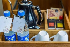 A wooden tray with two bottles of water, two white cups, a black kettle, and a box of tea bags. - Jin Meng Yuan Hotel (Zibo)