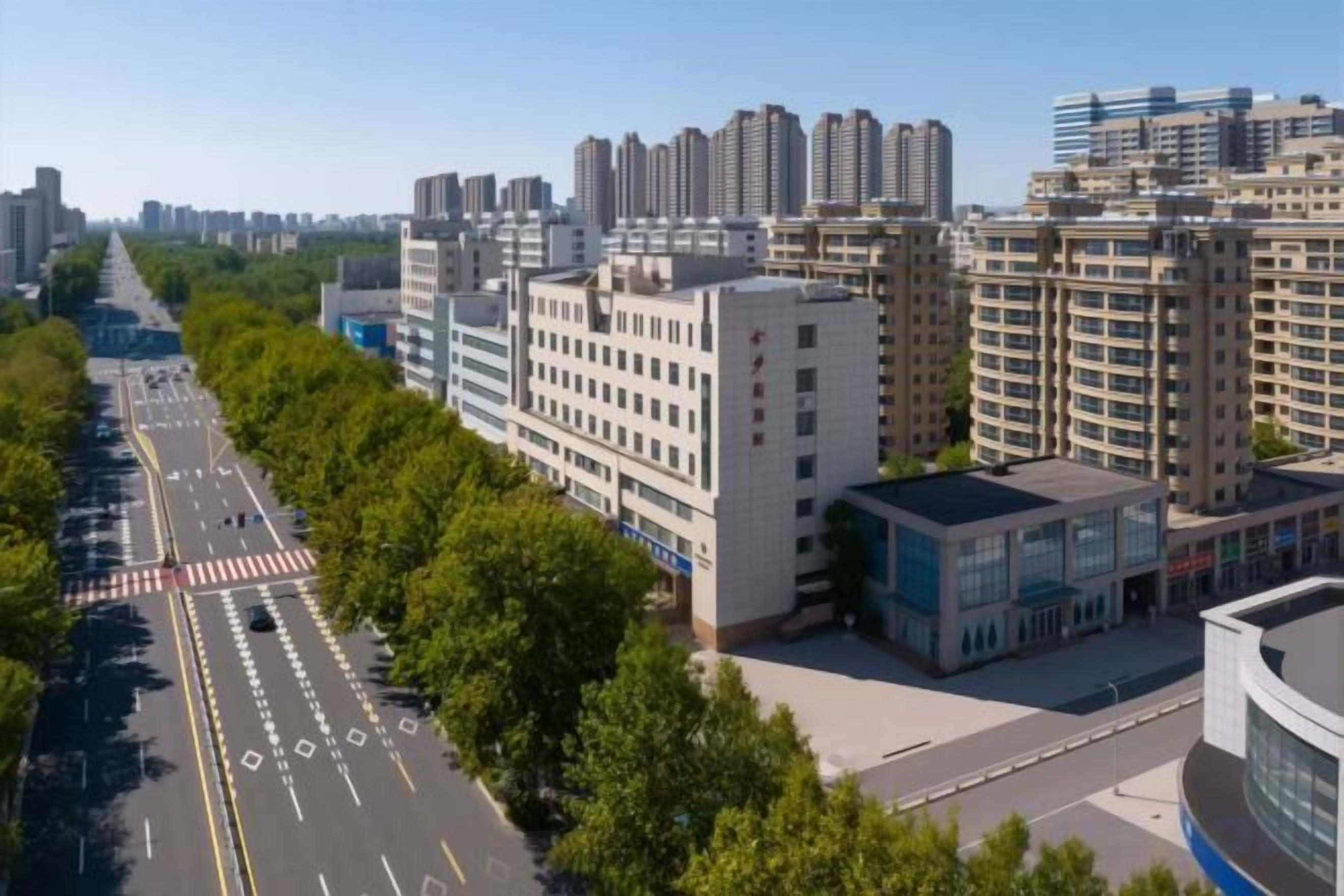 A multi-story building with a flat facade, surrounded by trees and a clear sky.