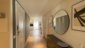 Un couloir avec un plancher en bois, un miroir et un tableau encadré accroché au mur.
