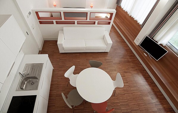 A compact kitchen with a sink, stove, and a dining area with a table and chairs. - Desuite Bolsena Loft (Milan)