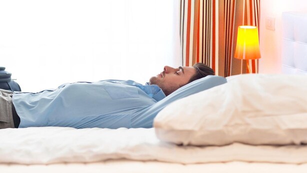 A person lying on a bed in a hotel room with striped curtains and a bedside lamp. - Desuite Bolsena Loft (Milan)