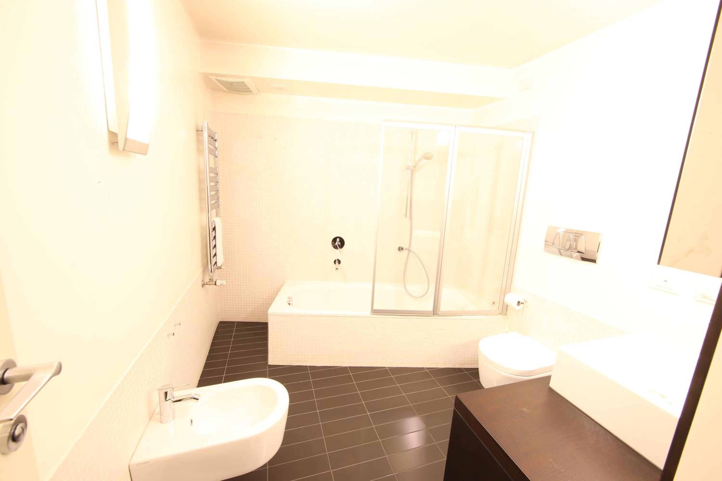 A modern bathroom with a bathtub, toilet, and sink.