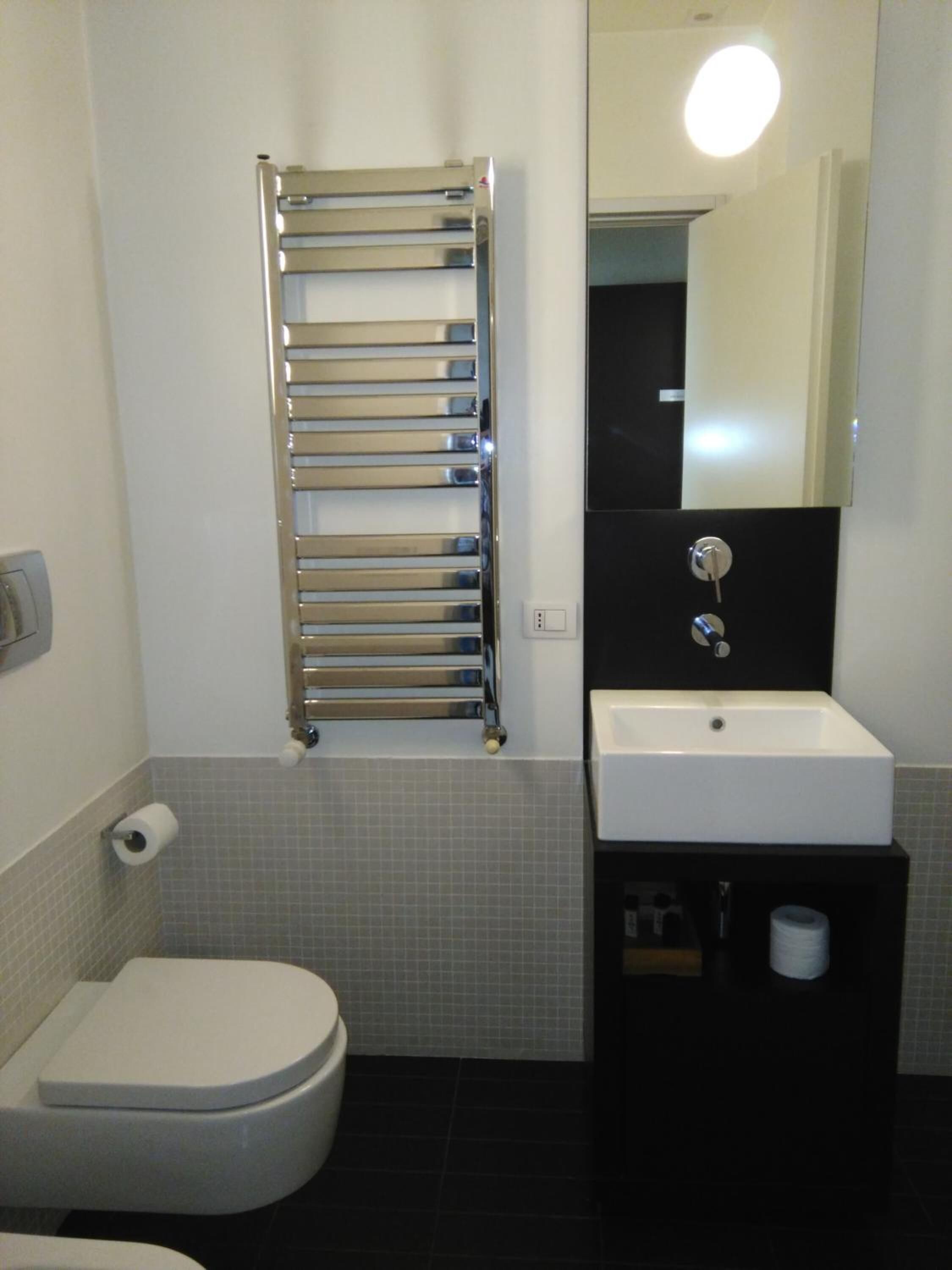 A modern bathroom with a toilet, a sink, and a towel rack.