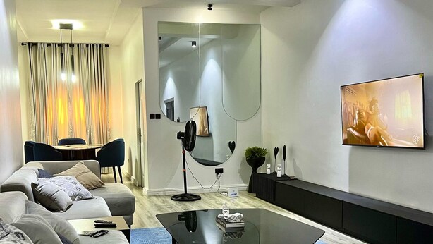 A modern living room with a sofa, coffee table, and a TV mounted on the wall. - 2bedroom luxury apt 24hrs light/wifi in lekki (Lekki)