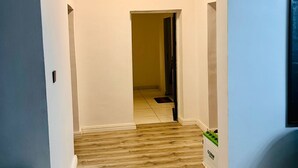 A hallway with a wooden floor, white walls, and a ceiling light. - 2bedroom luxury apt 24hrs light/wifi in lekki (Lekki)