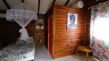 A room with a bed, a wooden wall, a chair, and a window with curtains.