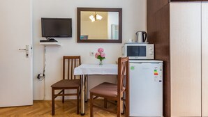 A small kitchenette with a microwave, a refrigerator, and a table with chairs. - Secret & Stylish Hideaway Apartments Zadar- 2 Room (Zadar)