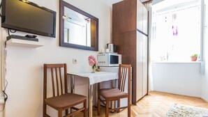 A small dining area with two wooden chairs, a white table, a TV mounted above, and a microwave on the table. - Secret & Stylish Hideaway Apartments Zadar- 2 Room (Zadar)