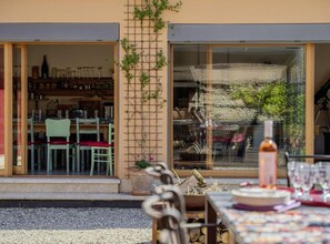 An outdoor dining area with a table set for two, a potted plant, and a view of the interior through a glass door. - Poolside Grand Retreat Villa (Sveti Lovrec)