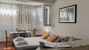 Une chambre d’hôtel avec un lit, un bureau, une chaise, une fenêtre avec des rideaux et un tableau encadré au mur.