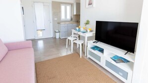 Ein modernes Wohnzimmer mit Flachbildfernseher, einer Couch und einem Essbereich mit Stühlen und Tisch.
