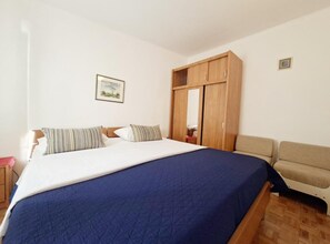 Ein Schlafzimmer mit einem Bett, einem Kleiderschrank, einer Couch und einem gerahmten Bild an der Wand.