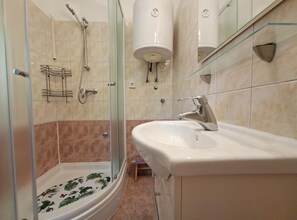 Ein modernes Badezimmer mit Duschkabine aus Glas, einem weißen Waschbecken und einem Spiegel.