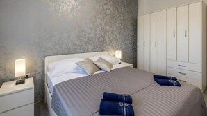 Een slaapkamer met een bed, nachtkastjes, een kledingkast en een gestructureerde muur.