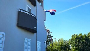 Een gebouw met een balkon en een vlag.