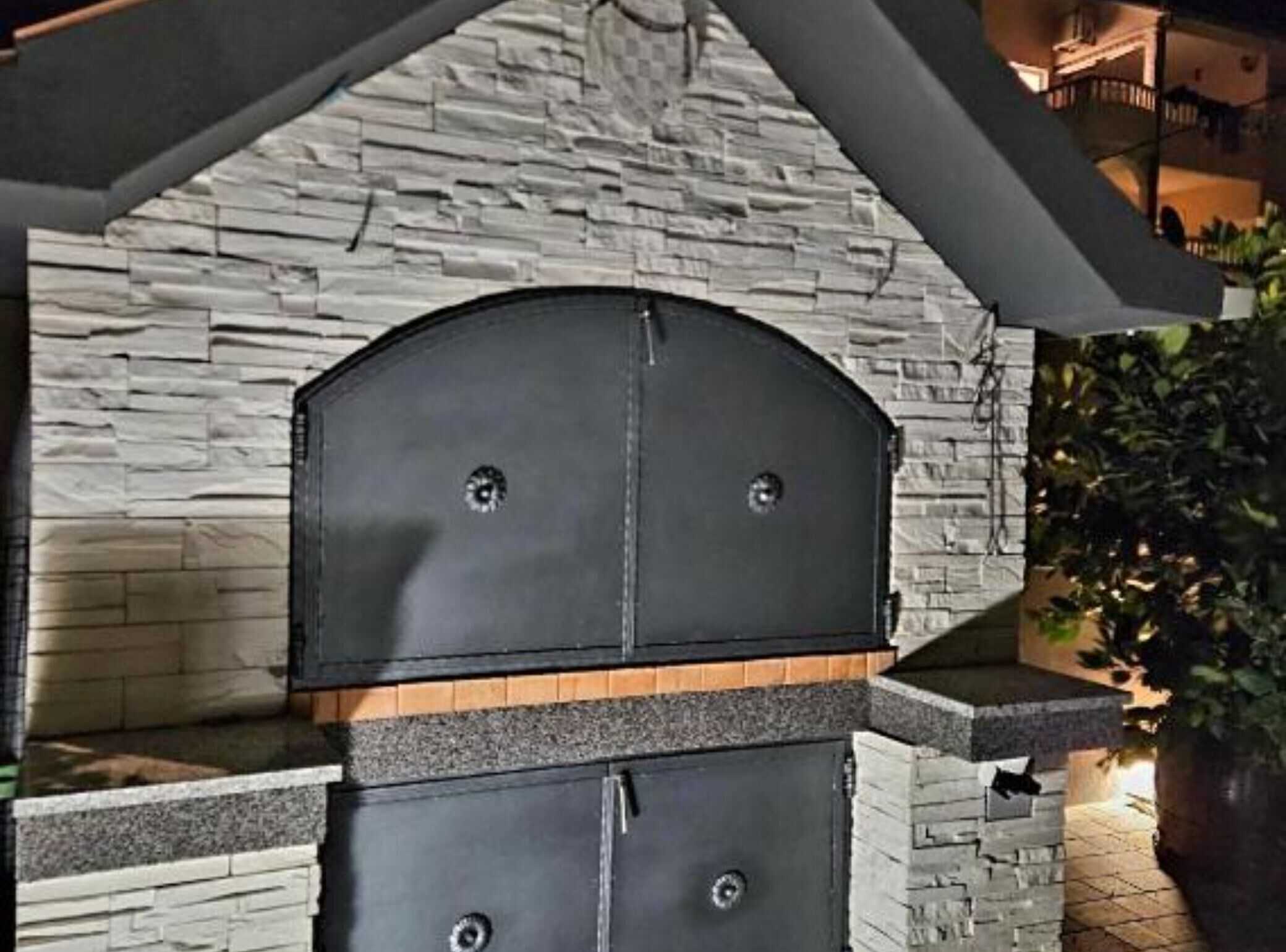 A stone wall with a black grill structure.