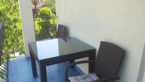 A balcony with a glass-top table and wicker chairs. - Apartments Lara Rab - One Bedroom Apartment with Balcony (Rab)