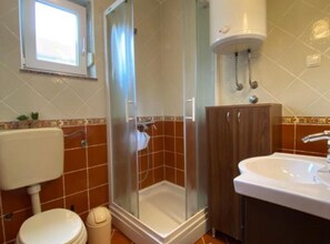 Ein Badezimmer mit Dusche, Toilette, Waschbecken und einem Schrank.