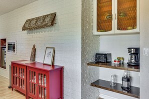 Eine Küche mit weißen Ziegelwänden, einem roten Schrank und einer Kaffeestation mit Toaster und Kaffeemaschine.