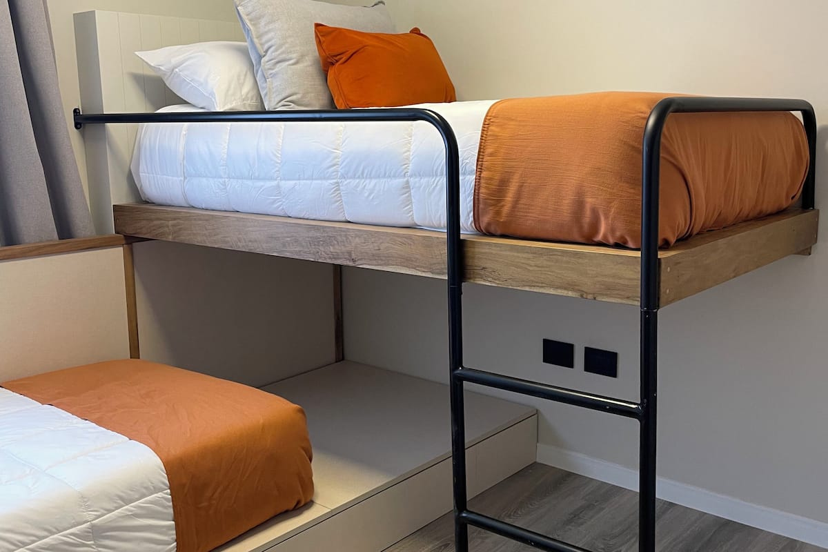 A bunk bed with a wooden frame and a white mattress.