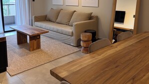 A modern living room with a sofa, coffee table, and wooden side table. There are abstract paintings on the wall and a large mirror. - Faz Flat (Córdoba)