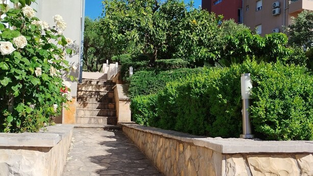 A stone staircase leading up to a building, surrounded by lush greenery and white flowers. - One-Bedroom Apartment With Terrace And Sea View (A1) (Trogir)