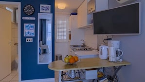 Une cuisine de taille réduite comprenant une table à manger, une horloge et un téléviseur à écran plat.