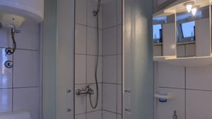 Une salle de bain avec une douche, un lavabo et un miroir.