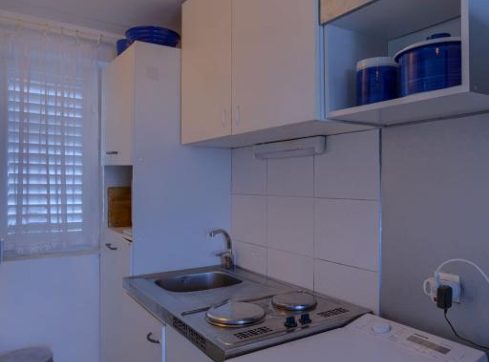 A compact kitchen with a sink, stove, and cabinets.