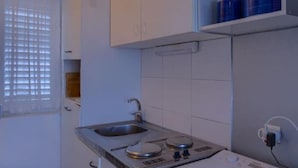 Une cuisine de taille réduite, équipée d’un évier, d’une cuisinière et de placards.