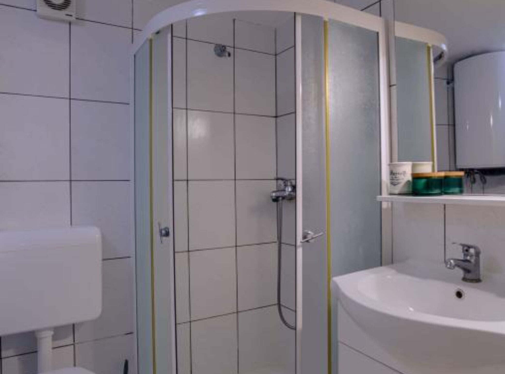 A bathroom with a white sink, a mirror, and a shower enclosure.