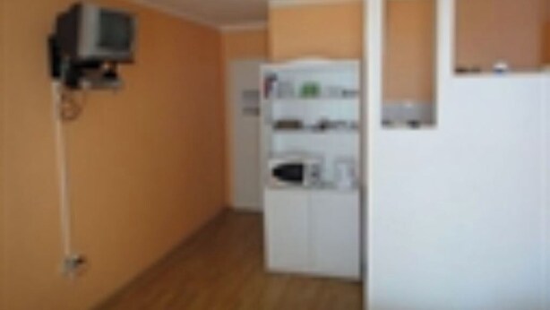 A room with a wooden floor, a white wardrobe, and a television mounted on the wall. - Seafront Apartments Pretner - Superior Studio (Orebic)