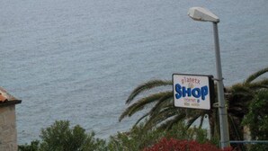 A sign for 'planetx SHOP' near a body of water with boats and a distant island. - Seafront Apartments Pretner - Studio with Terrace (Orebic)