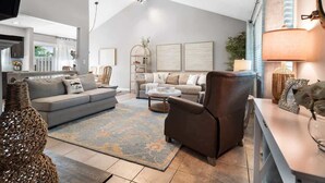 A spacious living room with a high ceiling, a sofa set, a coffee table, and a fireplace. - Lake Cottage Retreat-Hot Tub-Game Room (Avon Lake)