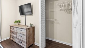 A room with a wooden dresser, a television mounted on the wall, and a closet with sliding doors. - Beautiful home in delightful Perry w/ King Bed (Perry)