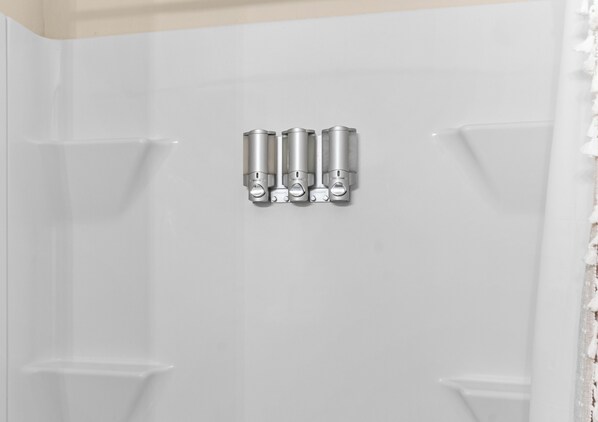 Un baño con una bañera blanca y cuatro accesorios metálicos en la pared.