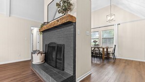 A spacious living area with a fireplace, wooden flooring, and a dining area with a table and chairs. - Beautiful home in delightful Perry w/ King Bed (Perry)