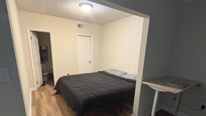 Una camera da letto con un letto, una scrivania e una porta che conduce al bagno.