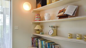 A kitchen with shelves holding cookbooks, a scale, and a lamp. - Church View Apartment (Parkham, near Bideford)