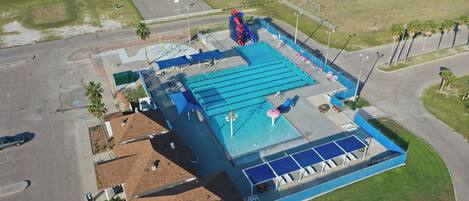 Una gran piscina con tobogán, cancha de baloncesto y cancha de tenis.