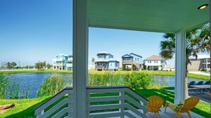 A covered outdoor area with a view of a lake and houses in the background. - La Concha Blvd #31 - (Port Aransas)