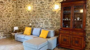 A room with a stone wall, a wooden cabinet, and a light blue sofa with yellow cushions.