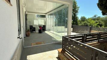 A modern glass-enclosed patio area with outdoor seating and a stone staircase.