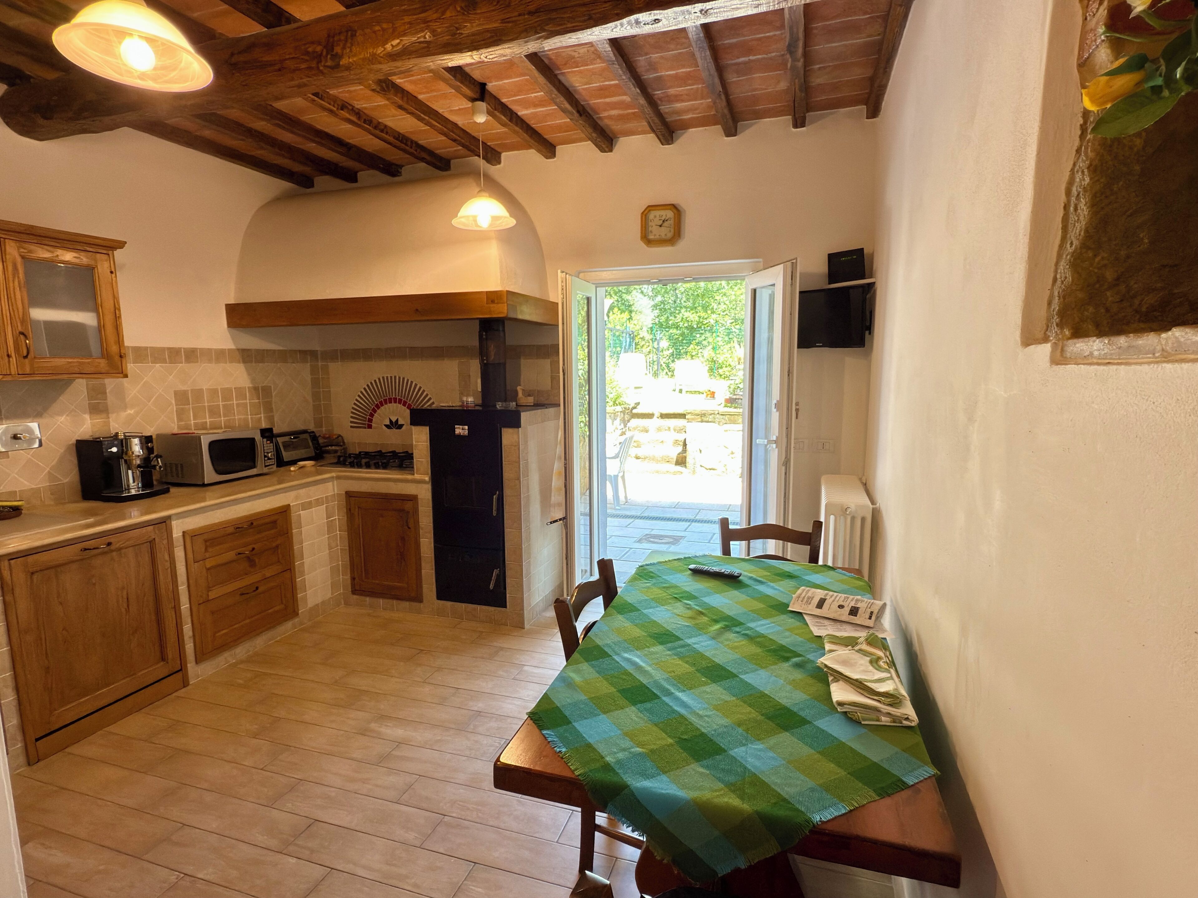 A kitchen with wooden cabinets, a microwave, and a stove. There is a dining table with a green checkered tablecloth.