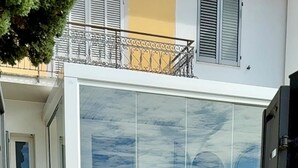 Une maison moderne dotée d’une grande baie vitrée, d’une terrasse dallée et d’un portail en métal.