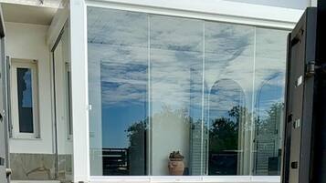 A modern house with a large glass window, a paved patio, and a metal gate.