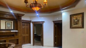 Un pasillo amplio con piso de mármol, puertas de madera y una lámpara de araña.